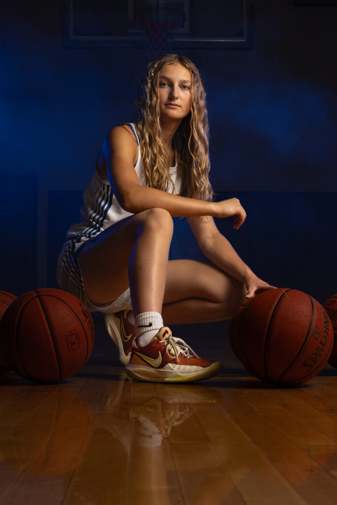 High school athlete posing in basketball uniform for portrait session