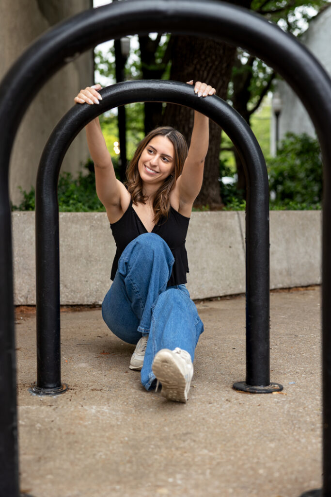 Senior girl posing playfully in Downtown Lawrence with metal bike rack
