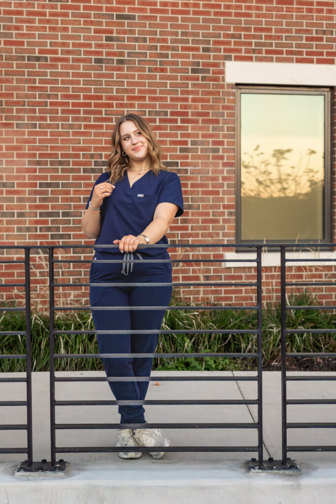 University of Kansas campus senior photos, Free State senior wearing blue nursing scrubs with stethoscope and KU pendant
