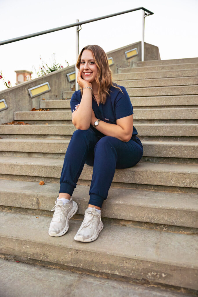 University of Kansas campus senior photos, Free State senior wearing blue nursing scrubs with stethoscope and KU pendant
