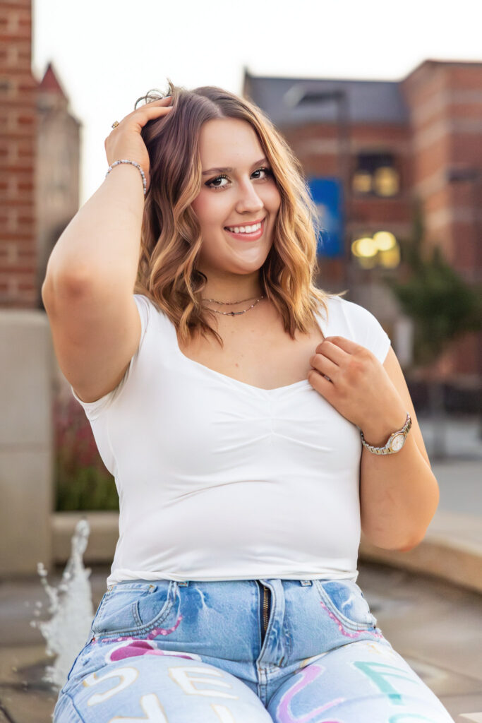 KU campus senior pictures in Lawrence KS, senior in jeans and white top during golden hour