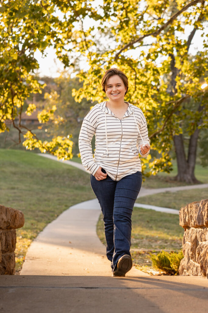 Amelia walking on a path during golden hour senior photos on the KU campus in Lawrence, KS