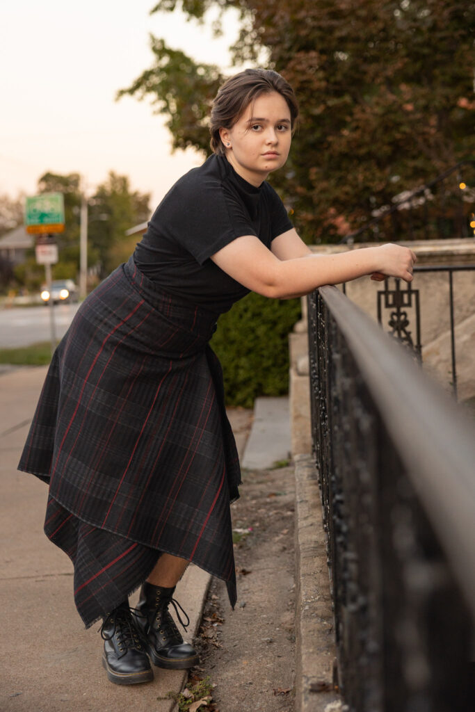 Amelia leaning on a railing during downtown Mass St senior portraits in Lawrence, Kansas