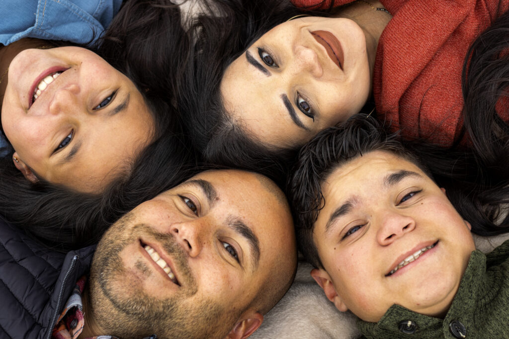 Family of four laughing together looking down at the camera during a senior family photo session in Lawrence KS