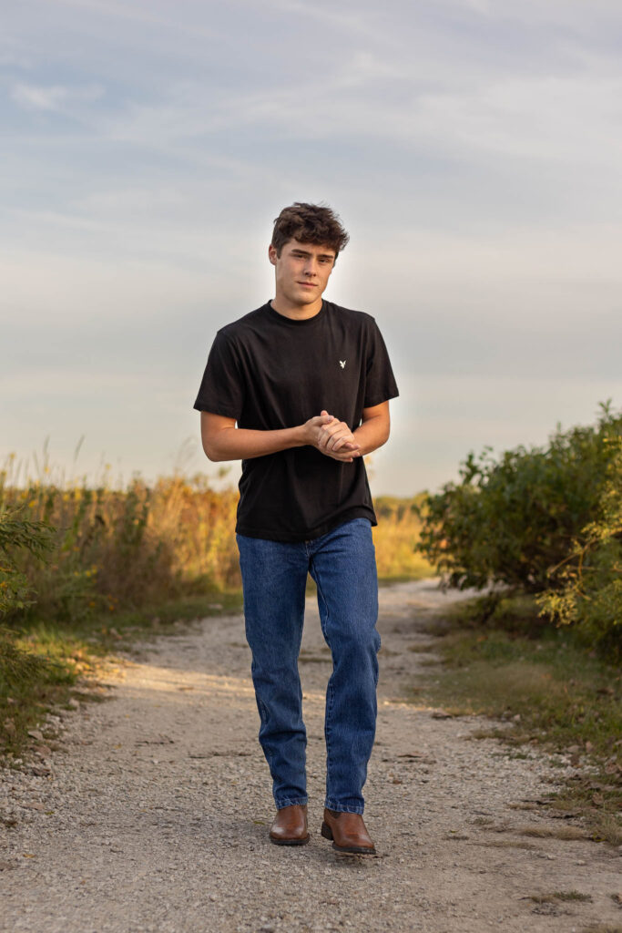 High school senior boy walking on a gravel path at Baker Wetlands in Lawrence