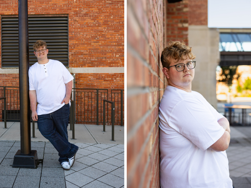 High school senior in a white henley and jeans leaning against a lamp post by a brick building on the KU campus in Lawrence, Kansas