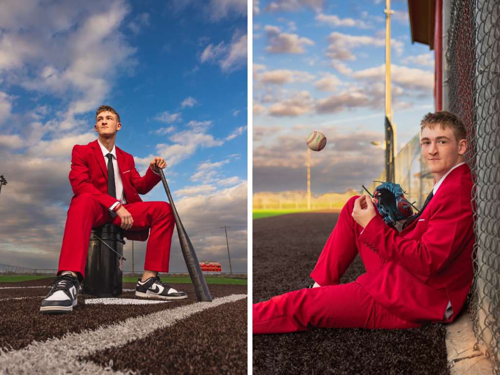 Senior guy in a red suit on a baseball field, sitting on a ball bucket with a bat and leaning against the outfield fence tossing a ball.