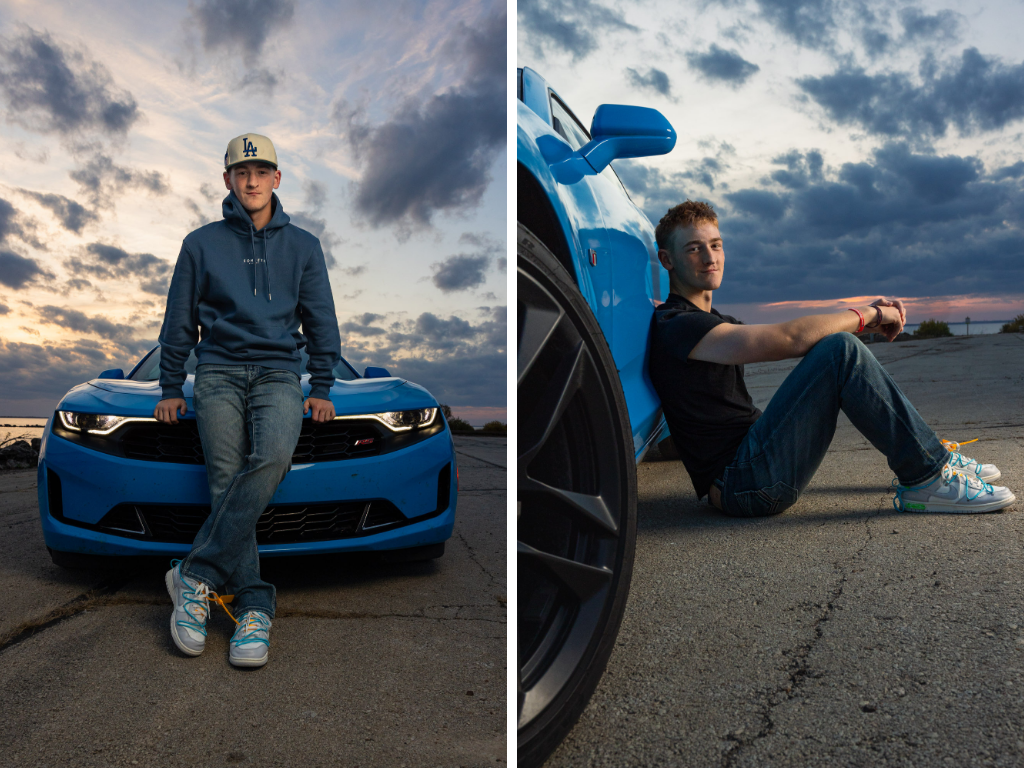 Senior boy in a navy hoodie and LA cap posing on and beside a bright blue Chevy Camaro at sunset.