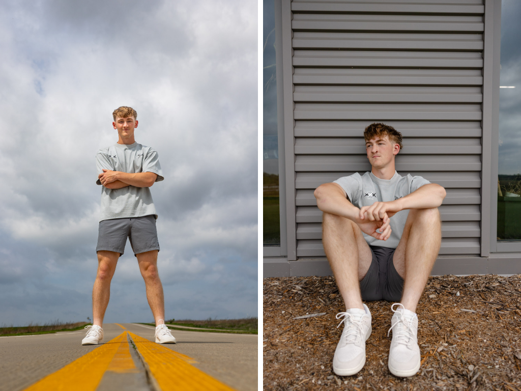 Senior guy standing with arms crossed on a country road center line and sitting against a metal building wall.